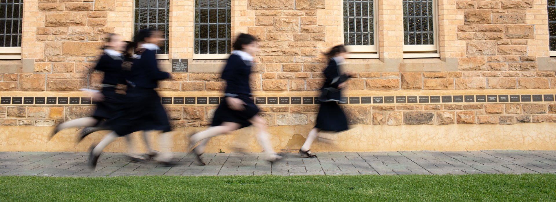 A group of students running in front of an old chapel